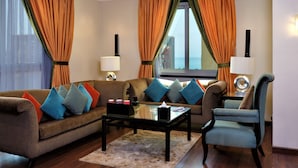 A living room with a sofa, armchairs, a coffee table, and a view of the ocean through large windows. - Boudl Kuwait (Salmiya)