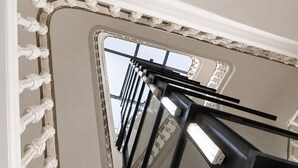 A view of a modern elevator with a metallic frame and glass panels, leading to a lower floor.