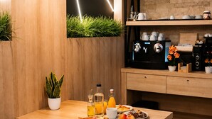 A modern kitchen with a wooden table, breakfast items, and a coffee machine.