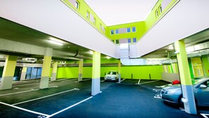 An indoor parking garage with green walls and white pillars, featuring multiple parking spaces and a few parked cars. - ibis Styles Brest Centre Port (Brest)