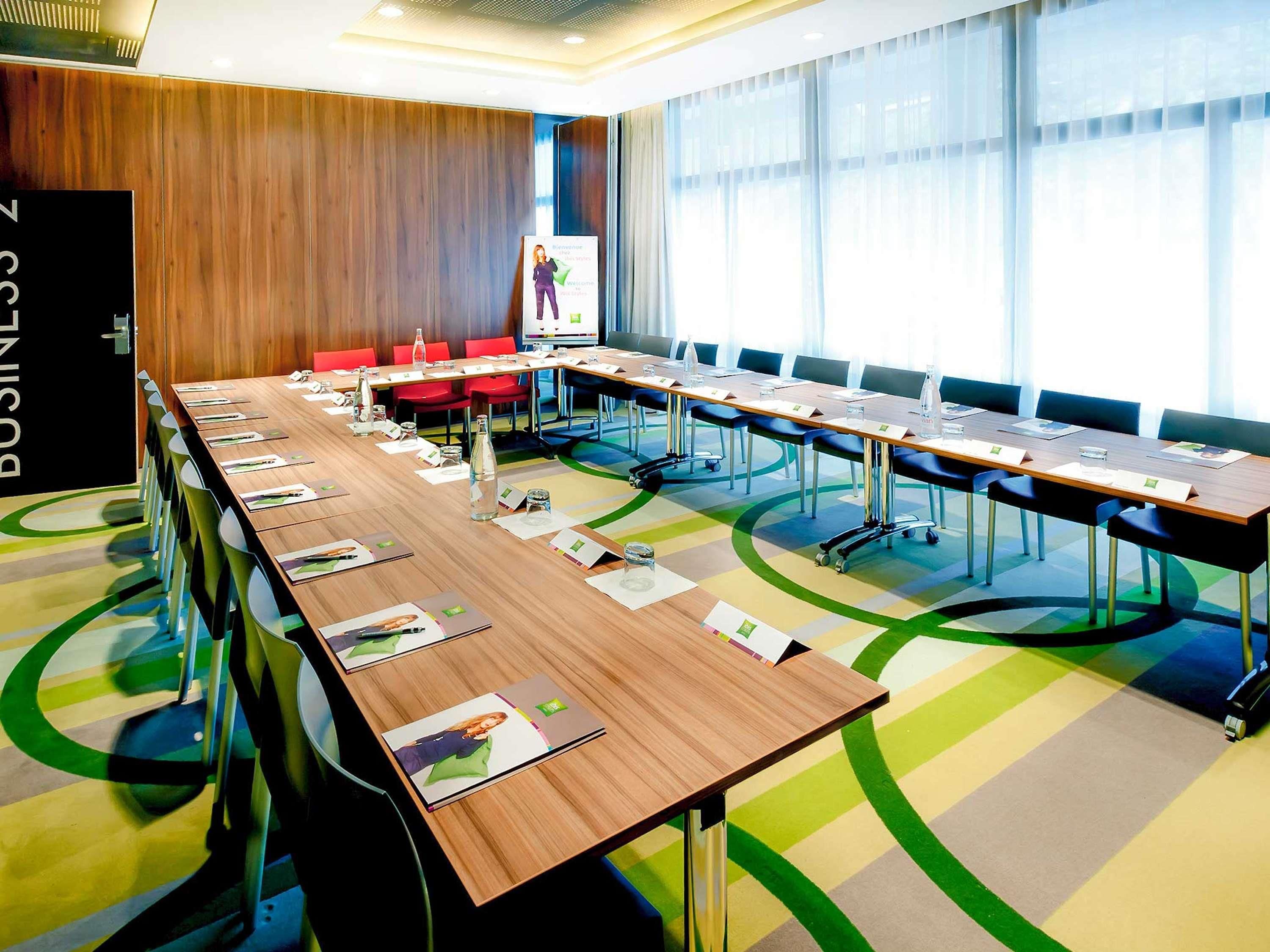Une salle de conférence équipée d’une longue table, de chaises et d’un écran de présentation.