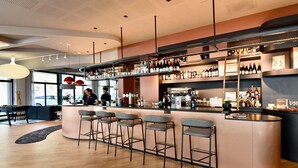 Una zona de bar con una barra curva, varios taburetes y una amplia variedad de botellas y vasos en estanterías.