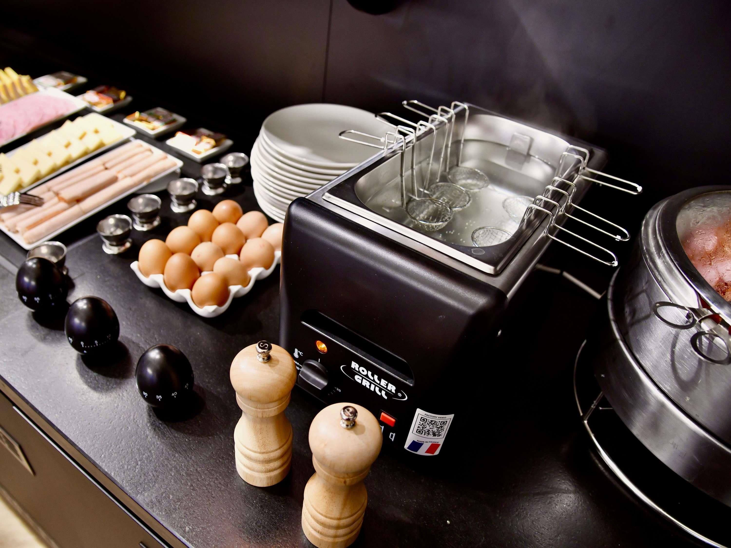 Un buffet avec un grill où les aliments sont préparés à la demande, des assiettes, des bols et des condiments.
