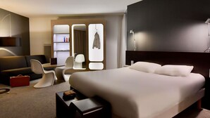 Una habitación de hotel moderna con una cama grande, un escritorio, una silla, un armario y un espejo.
