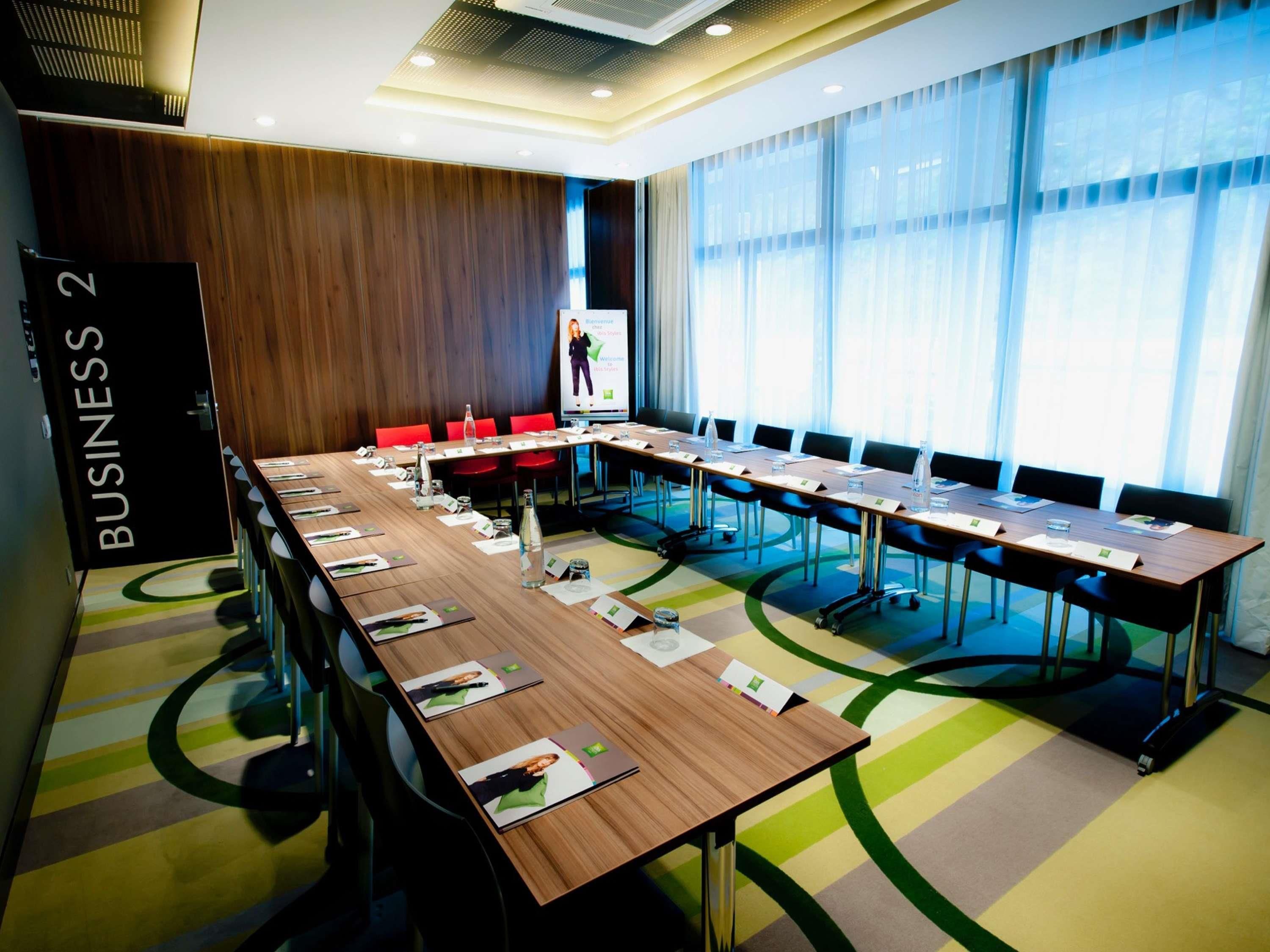 A conference room with a long table, chairs, and a presentation screen.