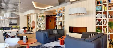 A modern living room with sofas, a fireplace, and a bookshelf.