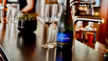 A bottle of Nicolas Feuillatte champagne on a bar counter with two glasses.