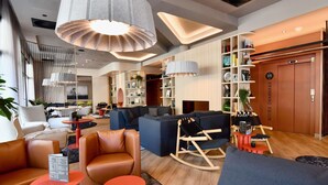 A modern hotel lobby with a seating area, bookshelves, and a reception desk. - ibis Styles Brest Centre Port (Brest)