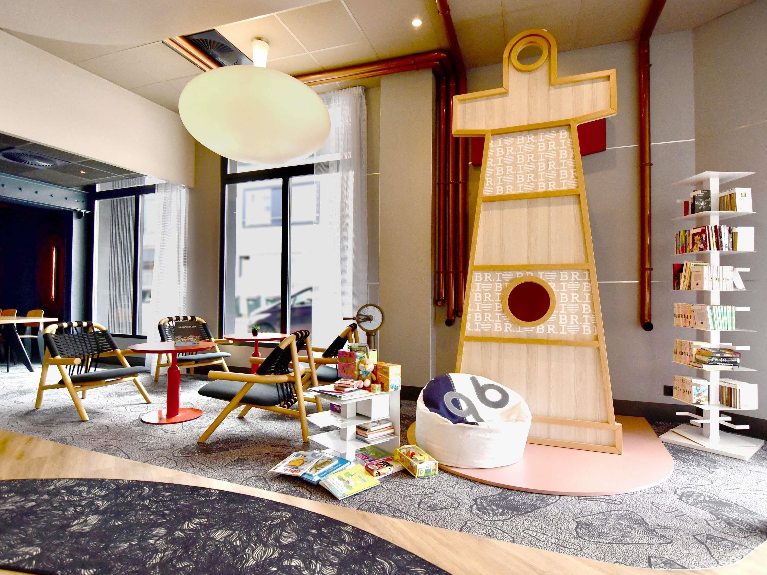 A children's play area with a large wooden structure, bookshelves, and seating.
