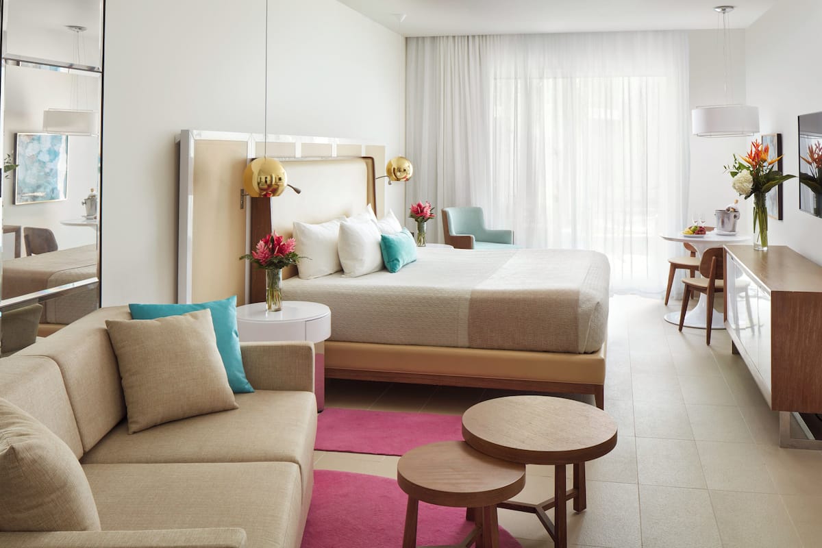 A modern hotel room with a bed, a sofa, a desk, and a chair.