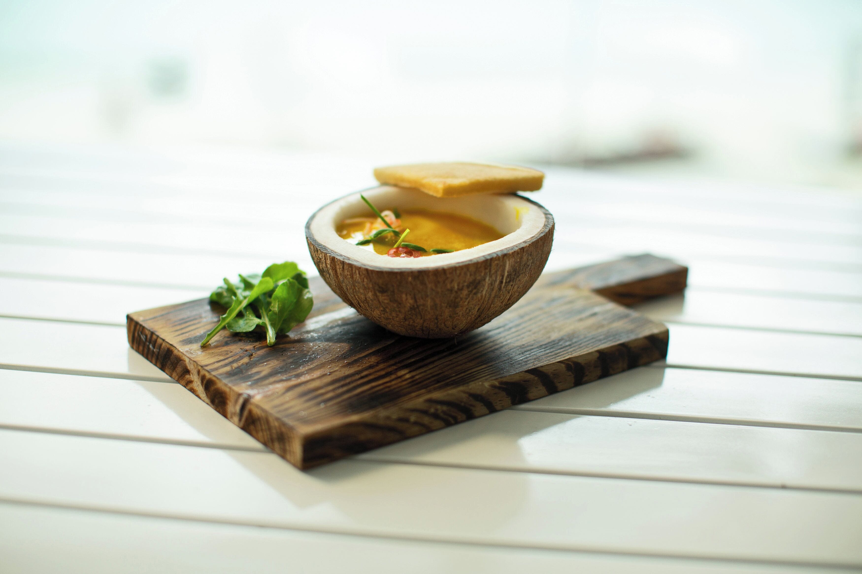 A wooden bowl with a lid on a white wooden surface.