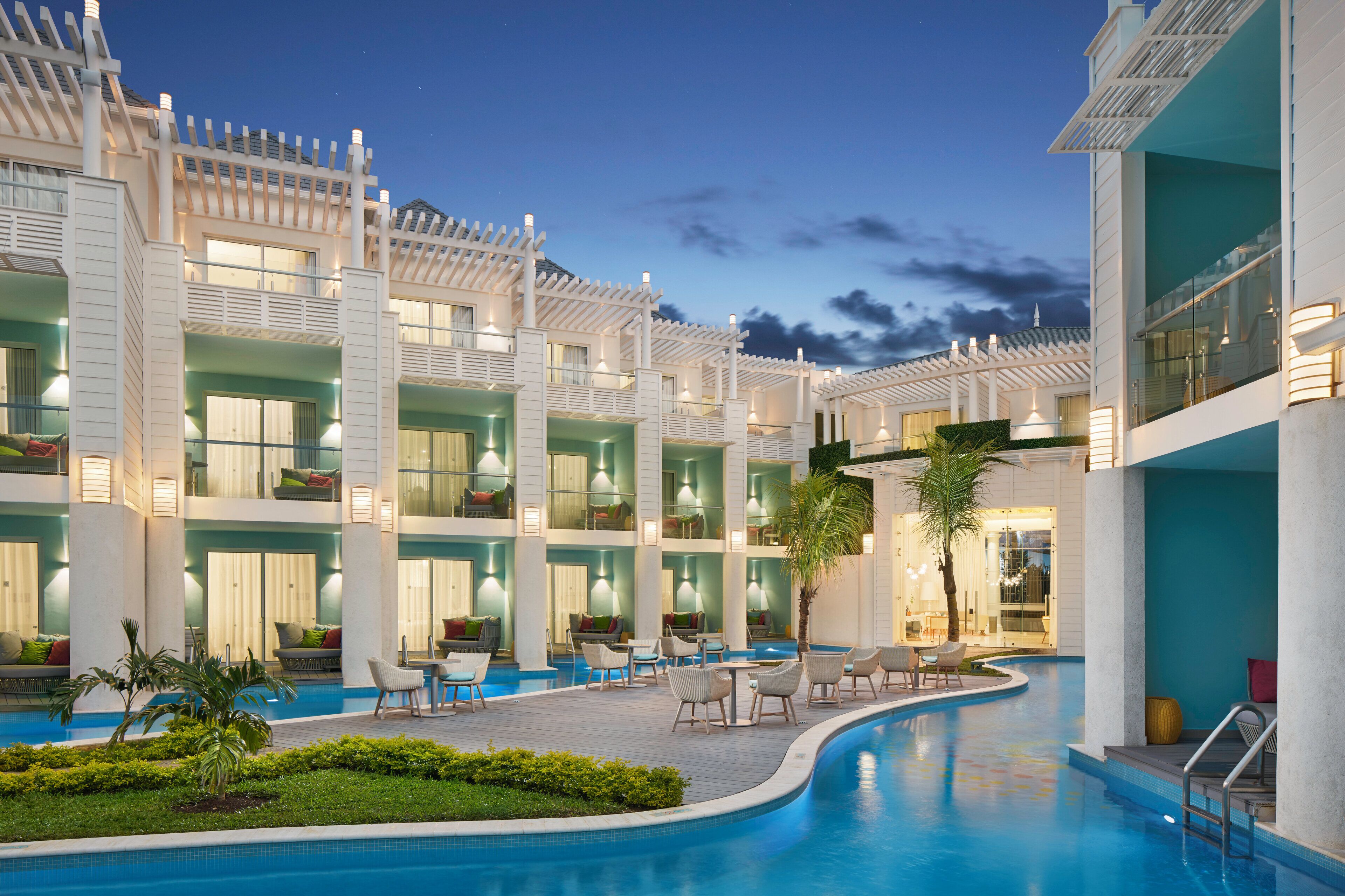 Un hotel con varios balcones, piscina y zonas de estar al aire libre.