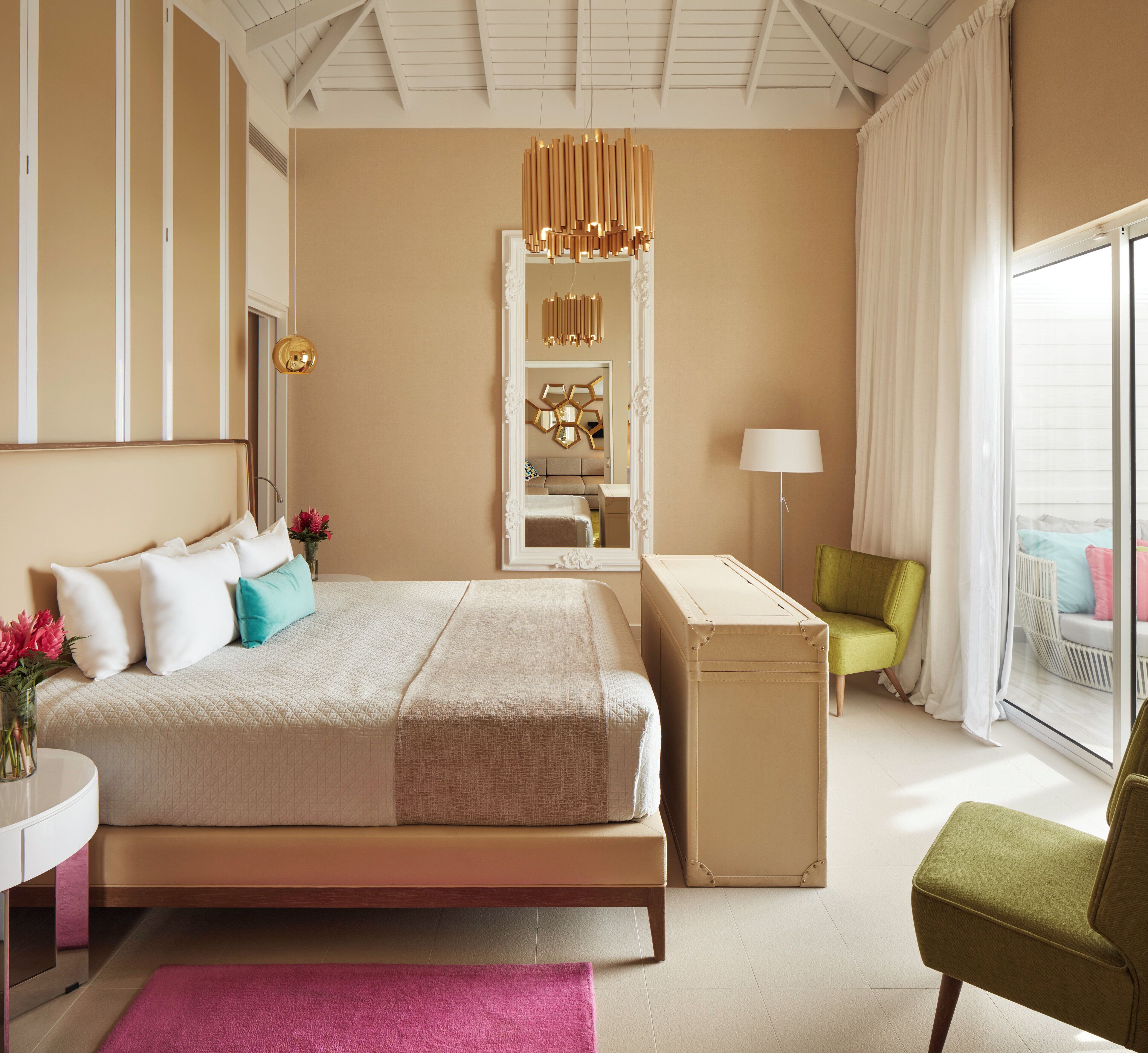 A modern hotel room with a large bed, a desk, a chair, a mirror, and a view of the outdoors.