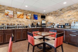 A modern kitchen with a brick wall, buffet setup, and seating area.