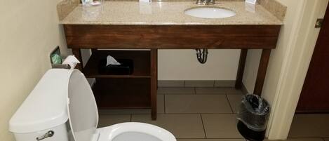 A bathroom with a white toilet, a sink, and a trash bin.
