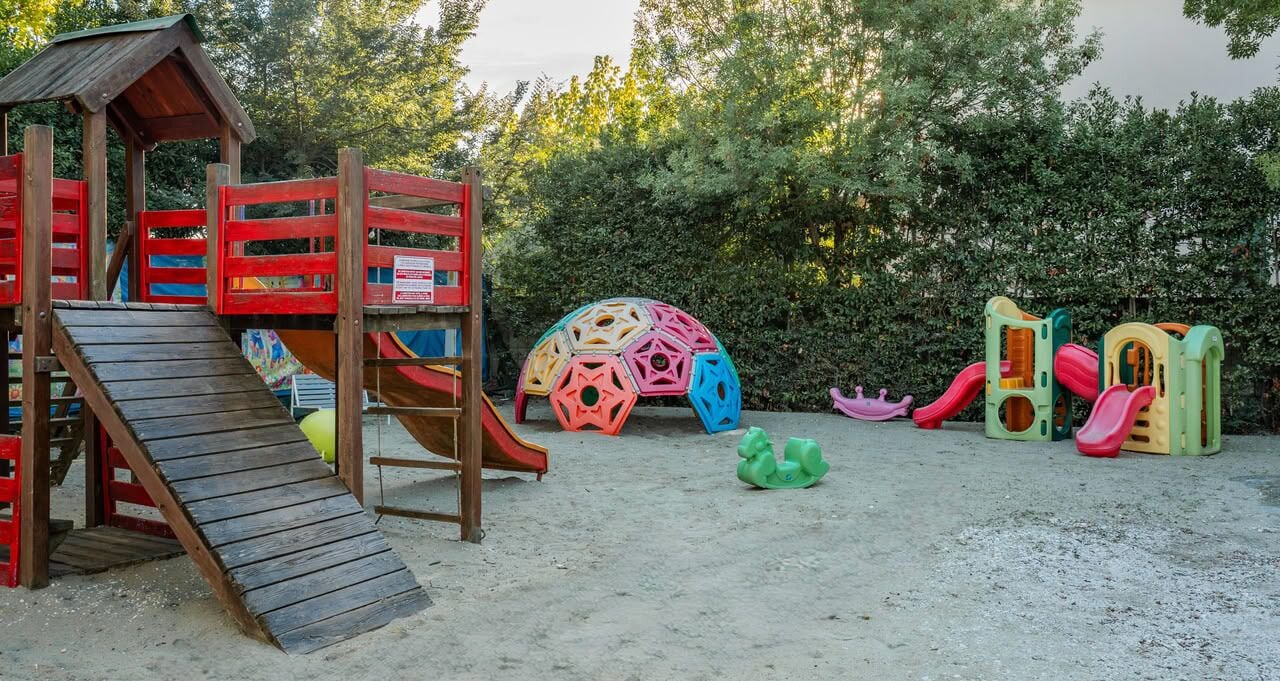 Un parque infantil con un tobogán de madera, estructuras para escalar y juegos de colores.