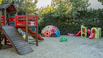 Un parque infantil con un tobogán de madera, estructuras para escalar y juegos de colores.