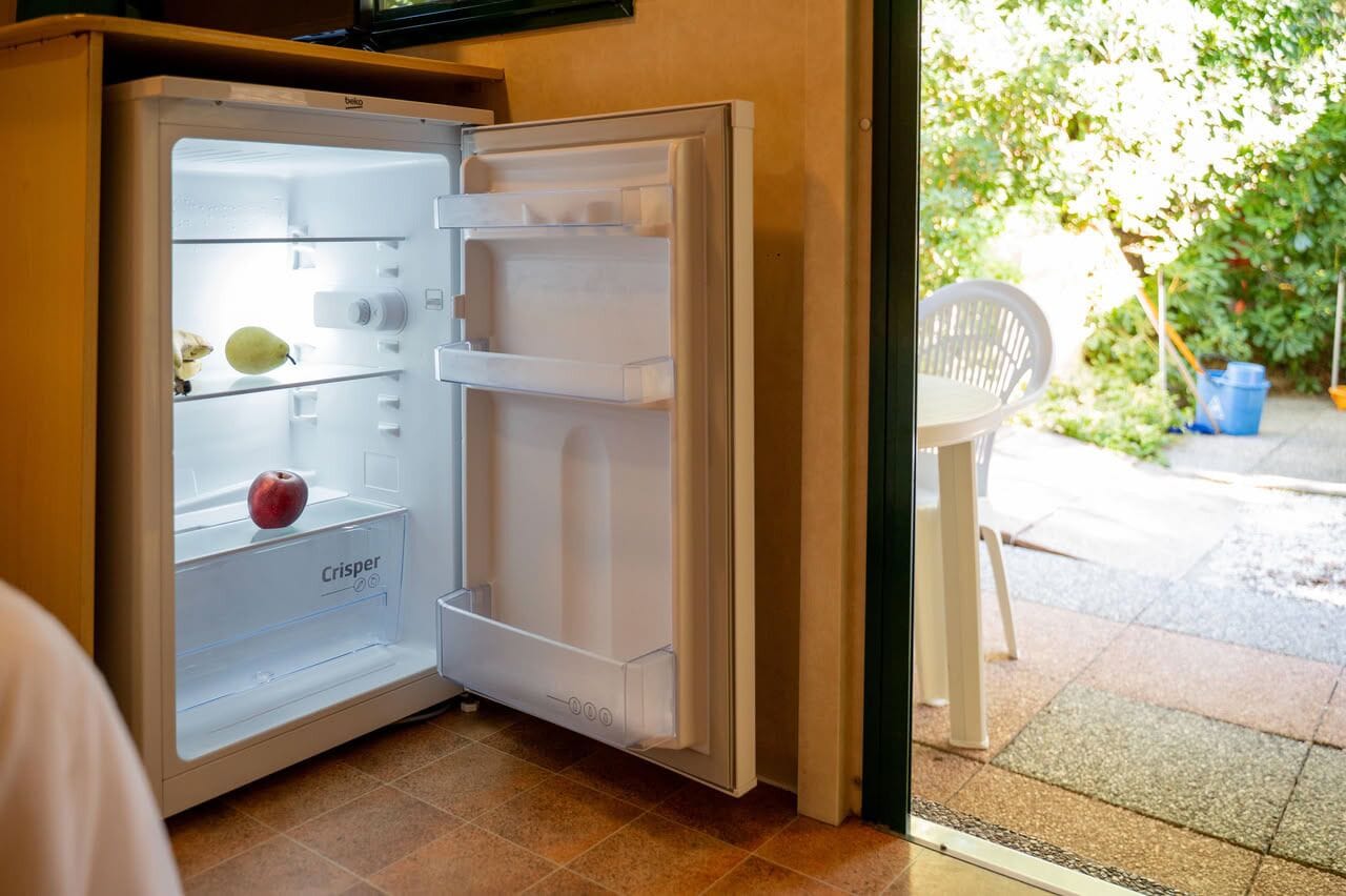 Een open koelkast met een 'Crisper'-lade, een enkele appel en een peer.