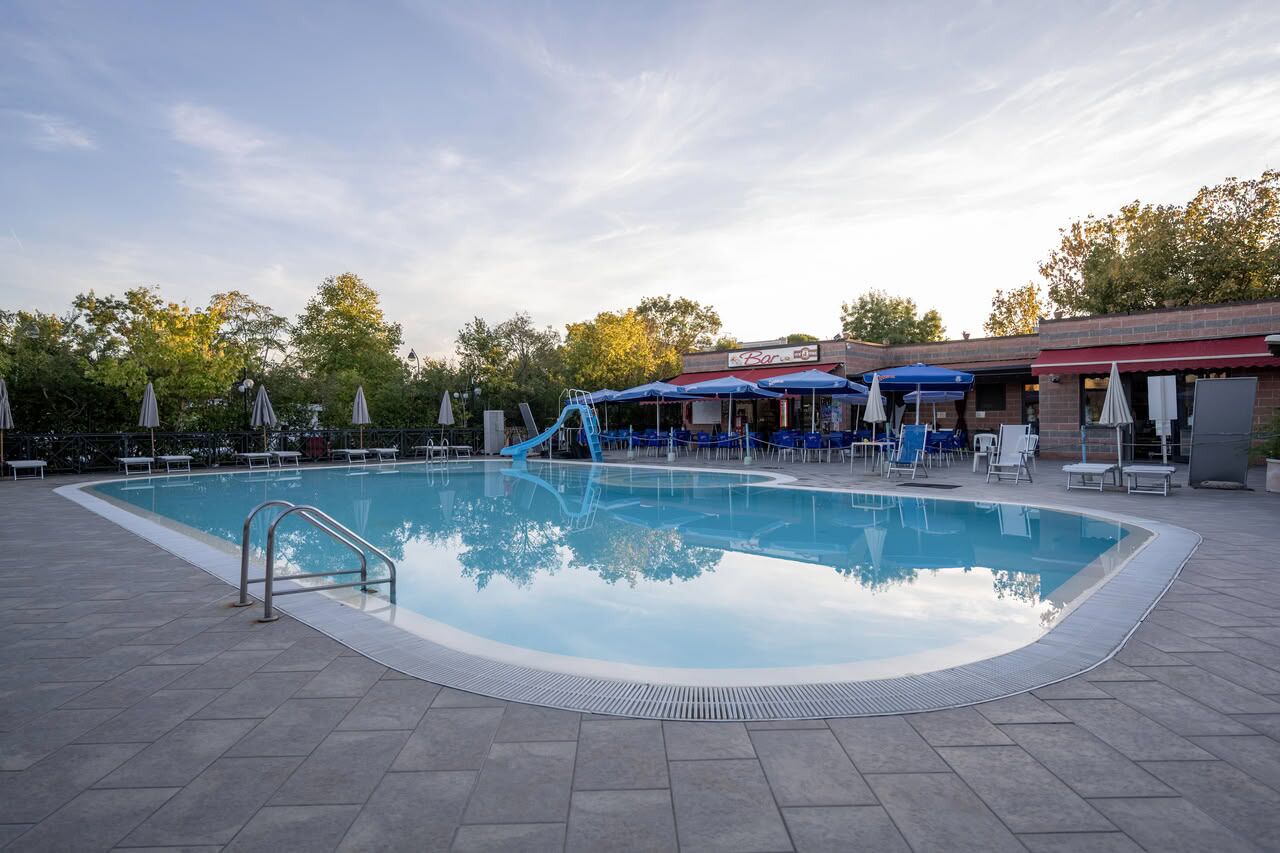 A swimming pool with a slide, lounge chairs, and umbrellas.