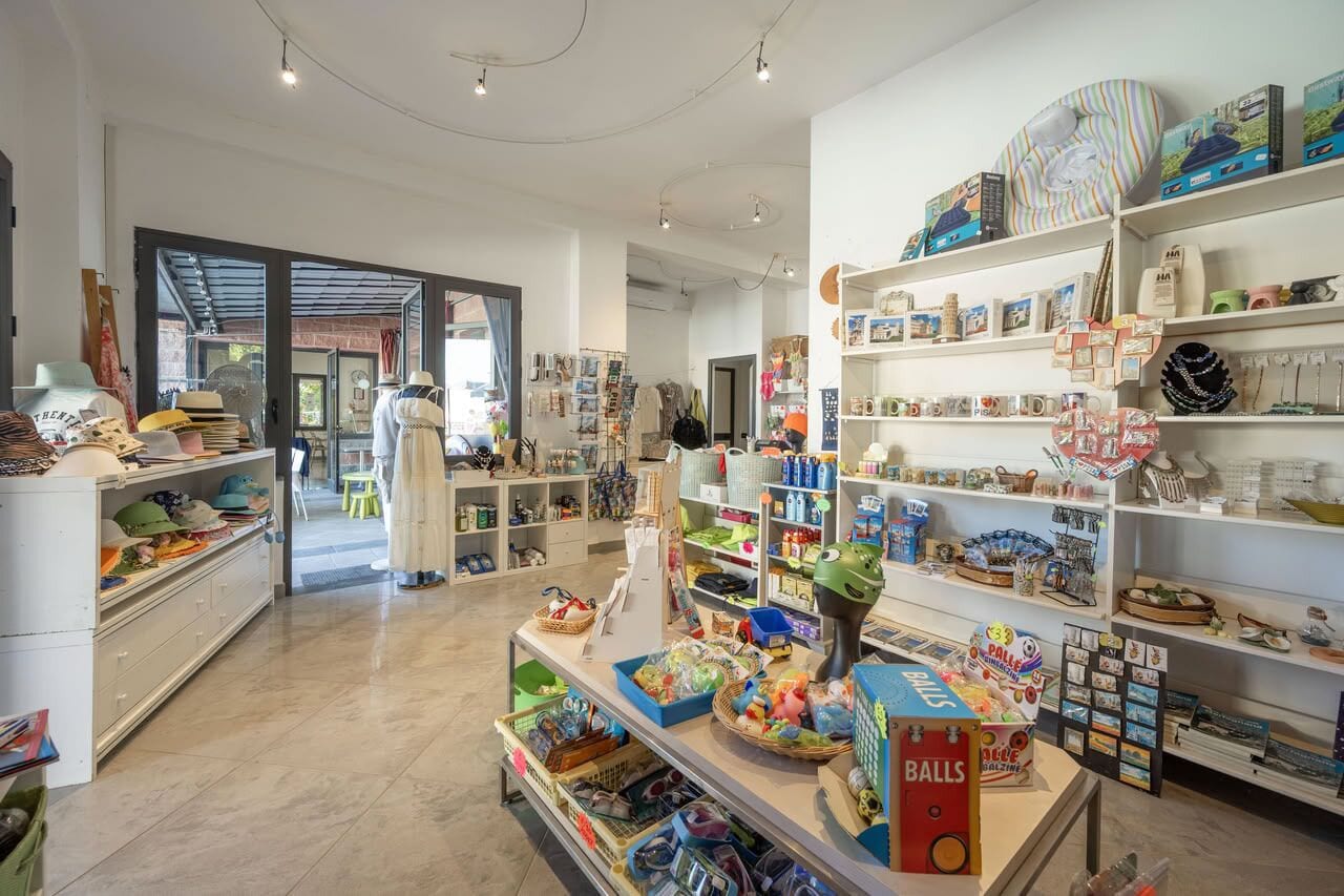 Un magasin bien éclairé, avec des étagères remplies de divers articles, notamment des chapeaux, des livres et des objets de décoration.