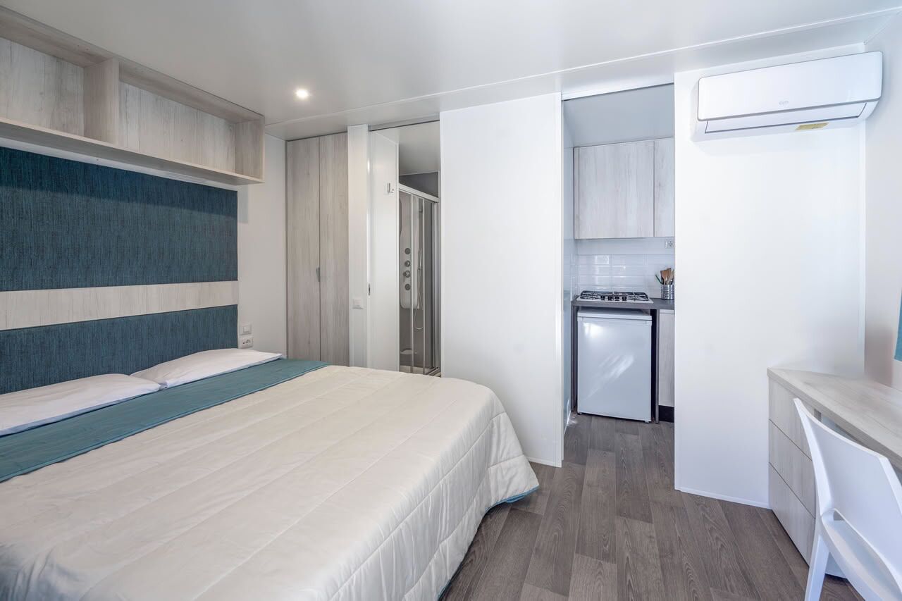 Una habitación de hotel moderna con cama, kitchenette y baño.