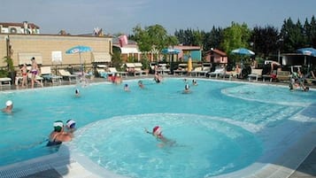 Una piscina al aire libre, sombrillas, sillones reclinables de piscina