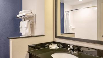 A bathroom with a sink, mirror, towel rack, and a shower curtain.