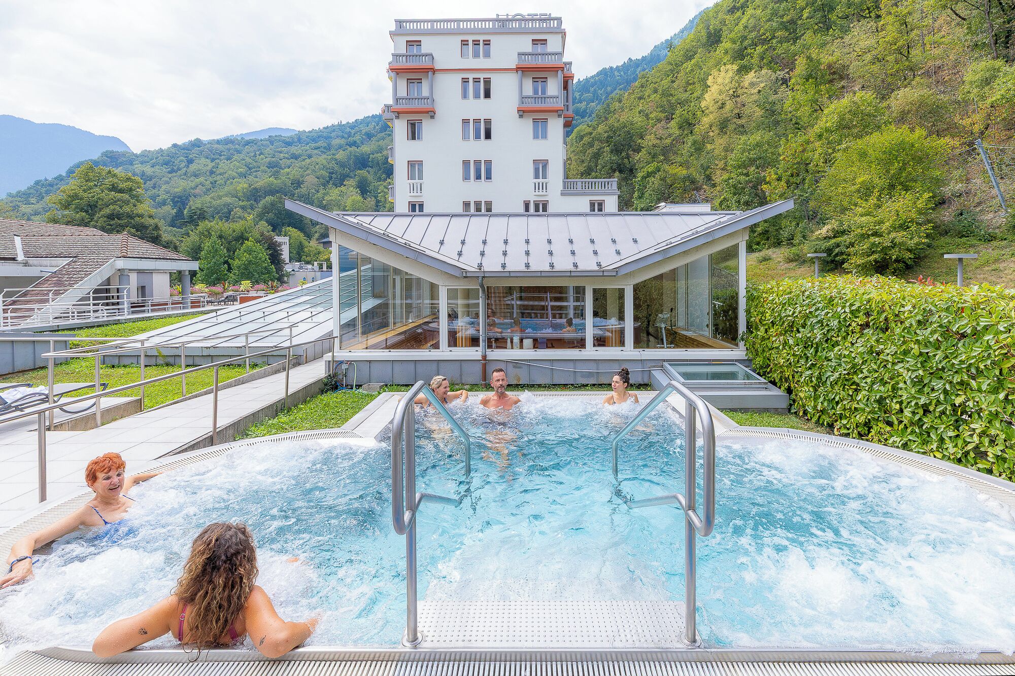 A hotel with a pool surrounded by lush greenery and mountains.