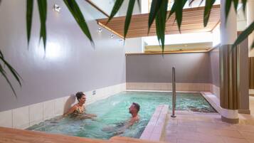 A spa area with a hot tub, tiled walls, and wooden flooring.