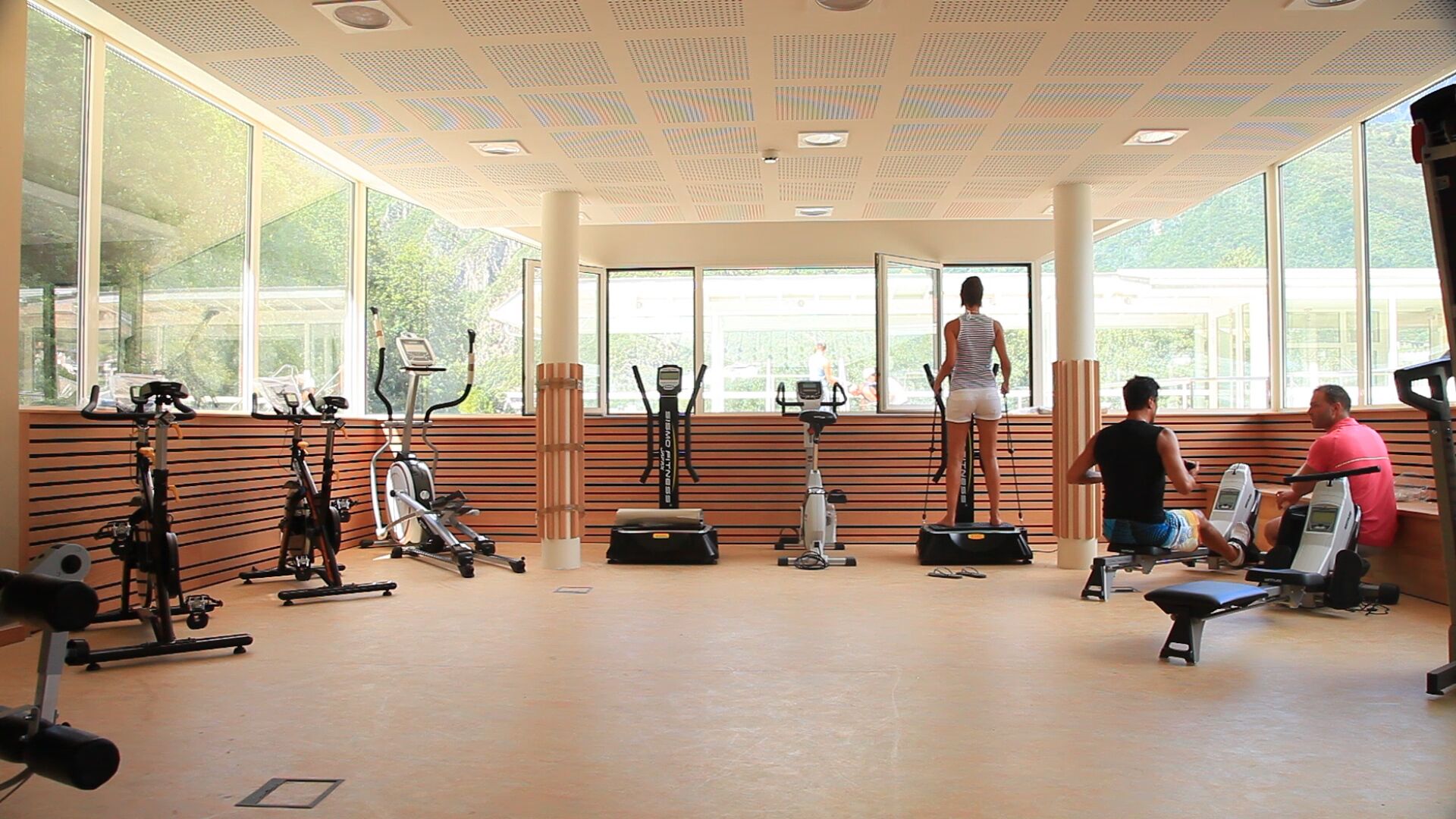 Un gimnasio con máquinas de cardio, una bicicleta vertical y una cinta de correr.