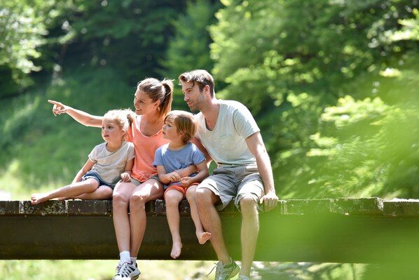 Une famille de quatre personnes assise sur une bordure en béton dans un parc.