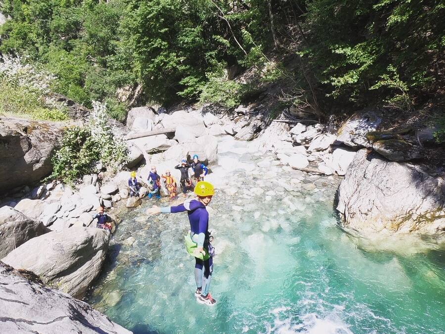 A group of people engaged in a water activity in a rocky, forested area.