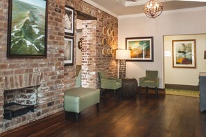 A room with a brick wall, a fireplace, and a seating area with chairs and a bench.