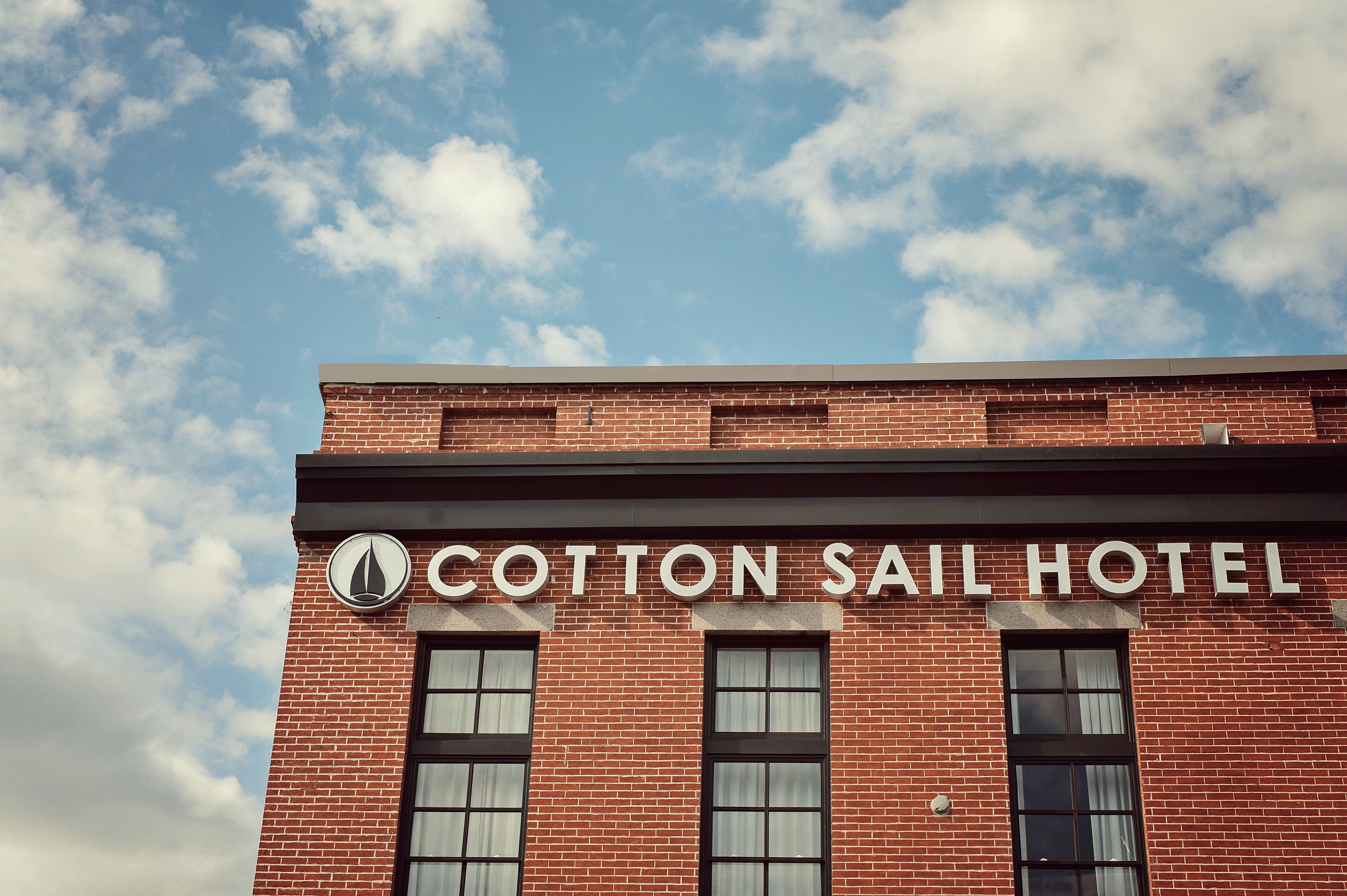 Un edificio de ladrillo con el letrero "Cotton Sail Hotel" sobre la entrada.