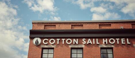 Un edificio de ladrillo con el letrero "Cotton Sail Hotel" sobre la entrada.
