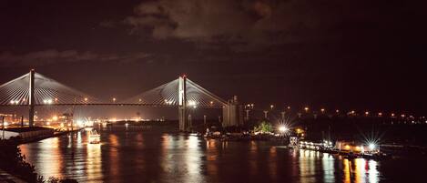 A nighttime view of a bridge with two large pylons and a river below.