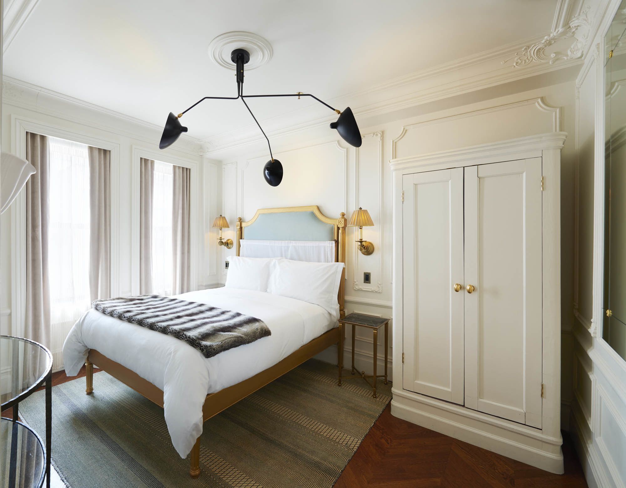 A spacious bedroom with a large bed, a wardrobe, and a chandelier.