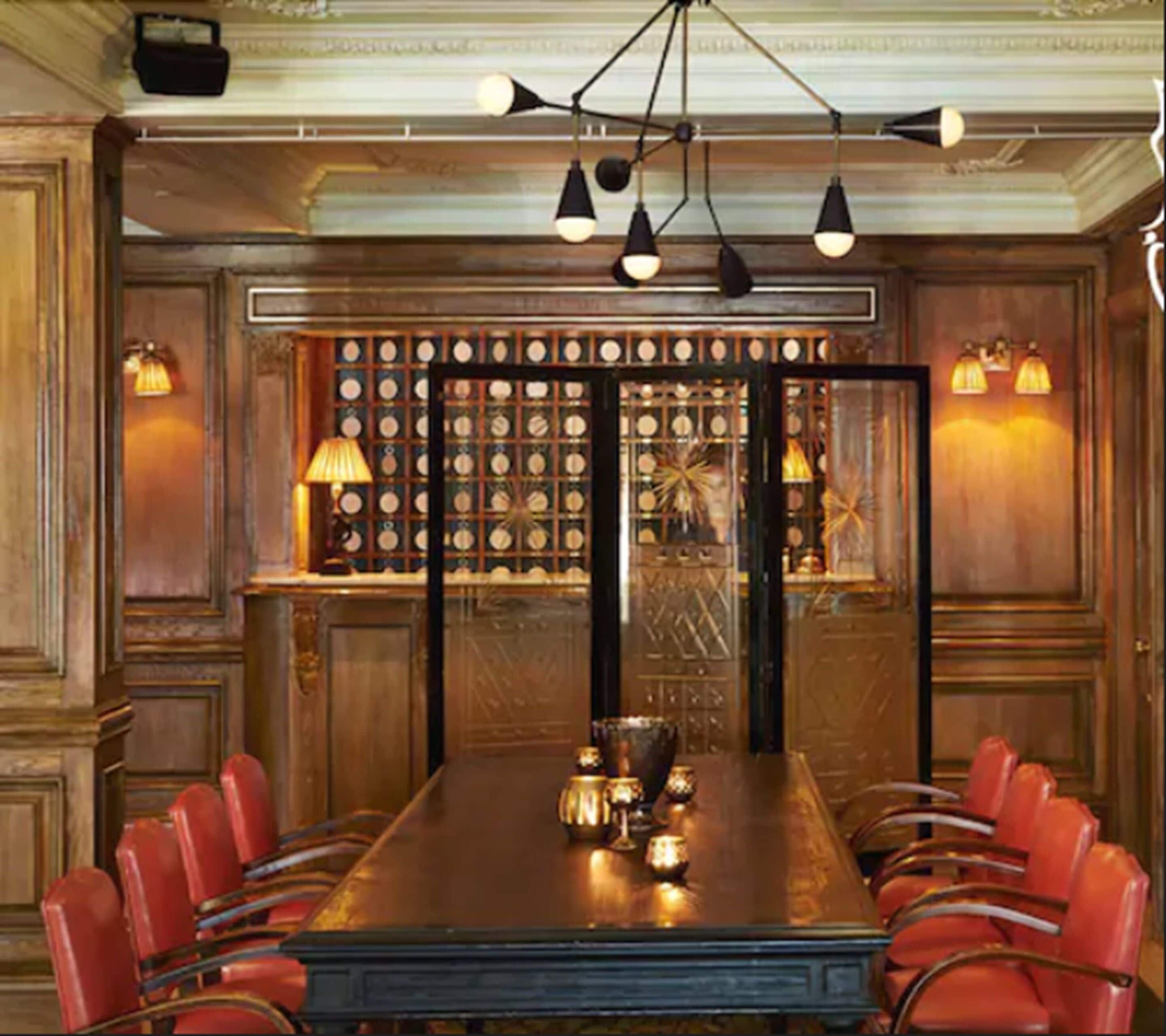A long dining table with red chairs, a chandelier, and a wall with circular decorations.