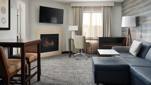 Habitación de hotel con chimenea, televisor de pantalla plana, sofá, escritorio y una silla.