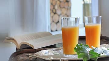 Due bicchieri di succo d'arancia su un vassoio con un libro e una foglia decorativa.