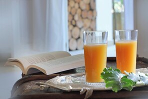 Two glasses of orange juice on a tray with a book and a decorative leaf. - Maison d'Enrì (Gallipoli)