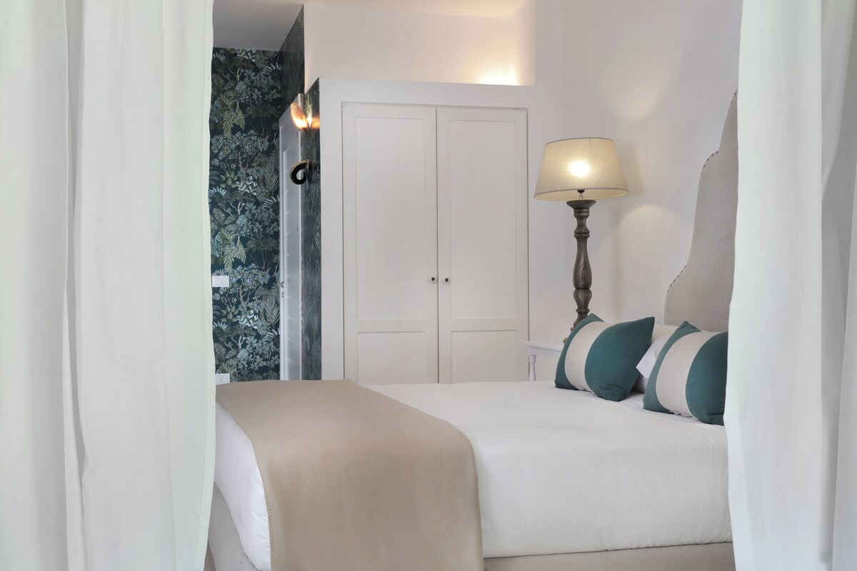 A hotel room with a bed, a nightstand, a lamp, and a wardrobe.