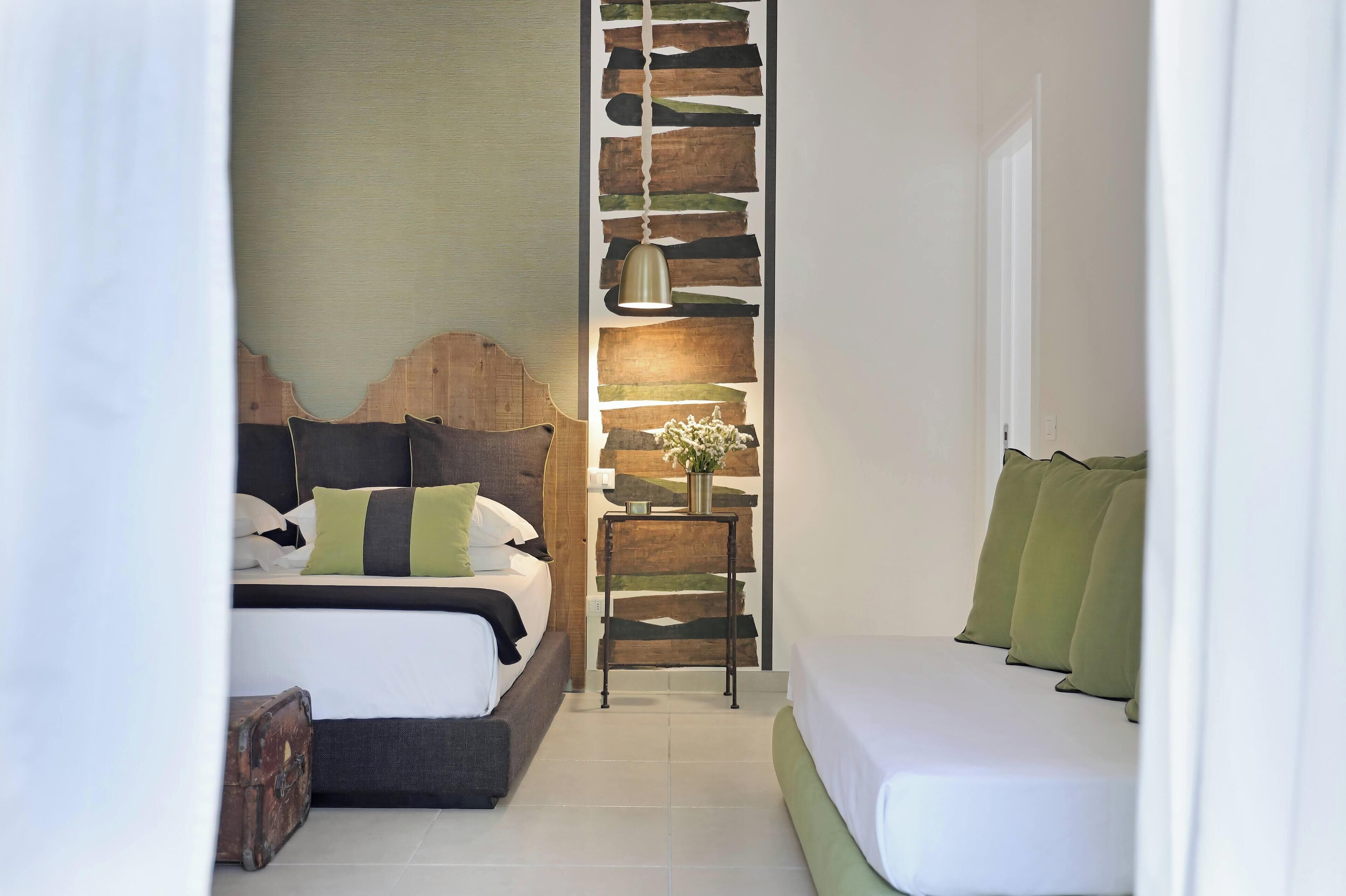 Un dormitorio moderno con cama, sofá, una mesita de noche con lámpara y un panel decorativo en la pared.