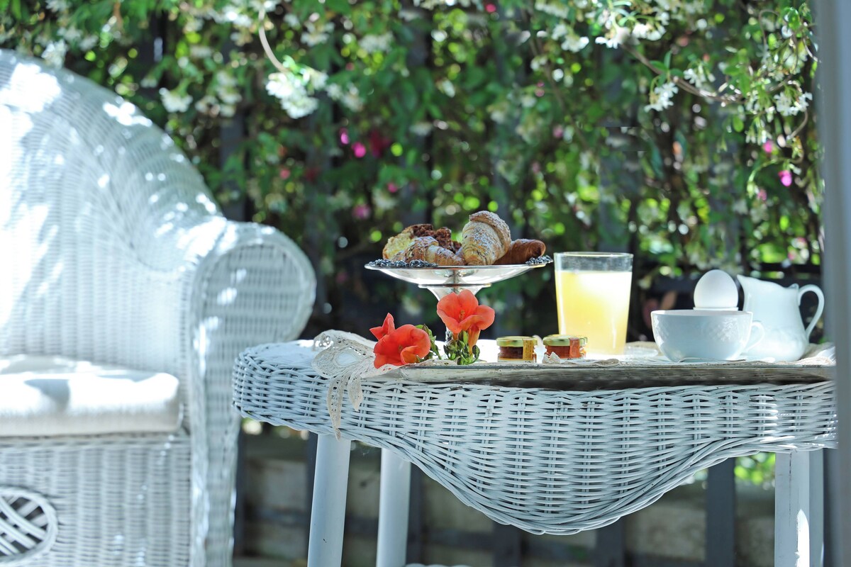 A wicker table with pastries, a glass of orange juice, and a white pitcher.
