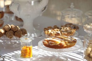 A table with various pastries and desserts, including a pie on a glass stand and a jar of jam. - Maison d'Enrì (Gallipoli)