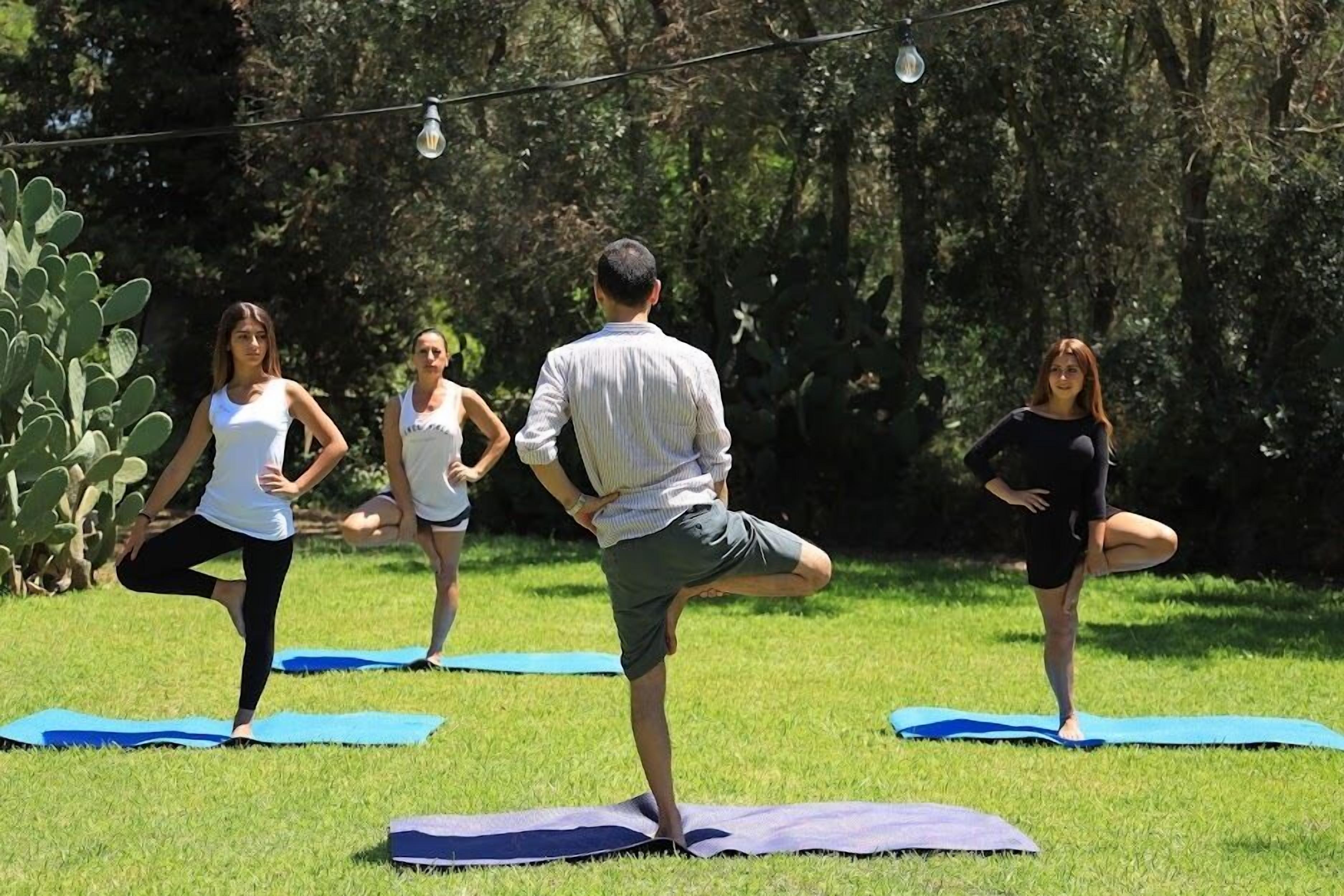 Un groupe de personnes pratiquant le yoga en plein air sur des tapis.