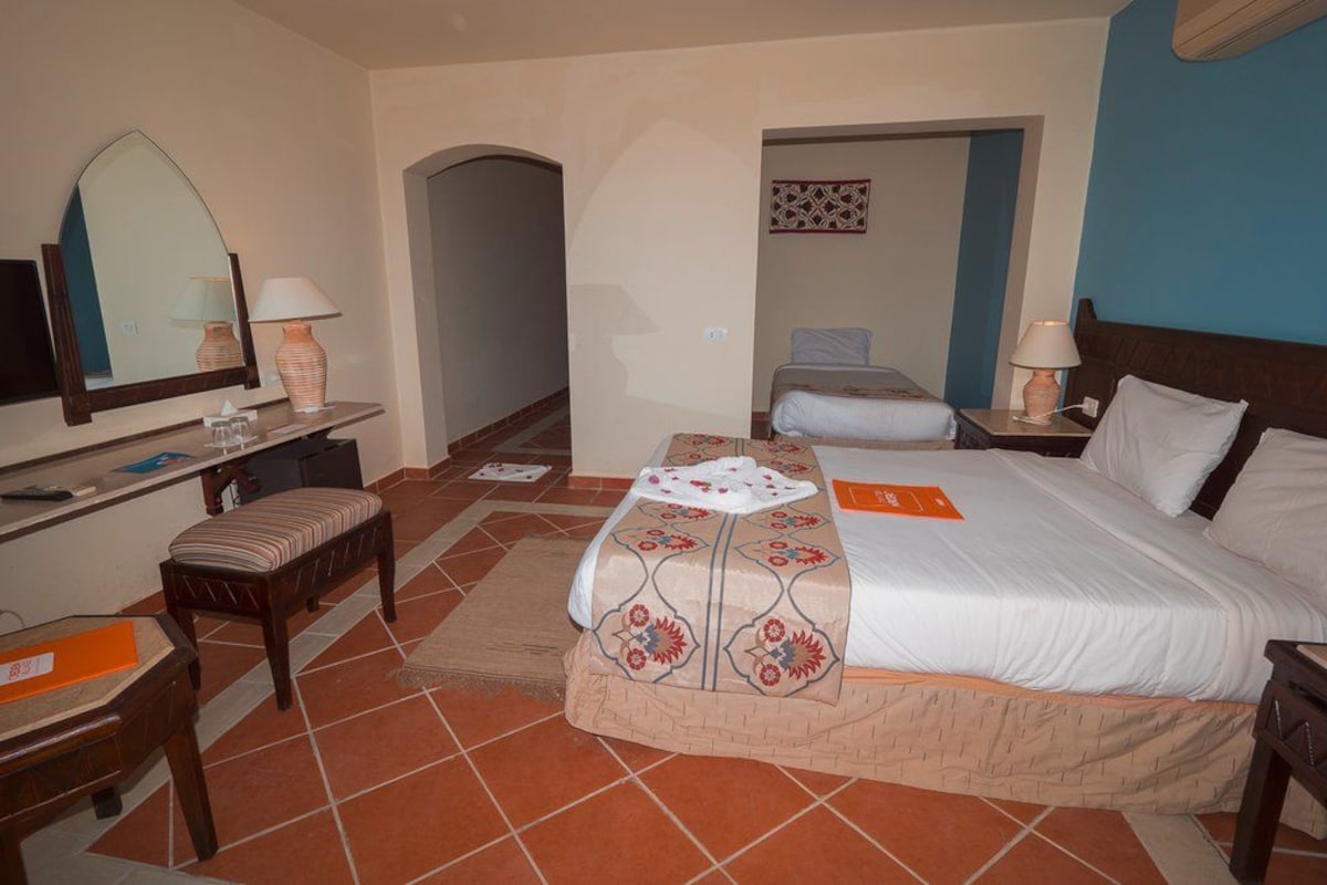 Ein Hotelzimmer mit Bett, Schreibtisch, Stuhl, Fernseher und Spiegel.