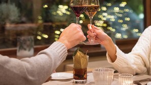 A dining table with two wine glasses, a glass of water, and a glass of red wine. A Christmas tree with lights is visible in the background. - QC Hotel Monte Bianco (Pre-Saint-Didier)