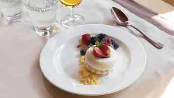 Une assiette de dessert avec des fruits rouges et un verre de vin blanc sur une table.
