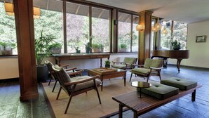 A spacious room with large windows, wooden furniture, and potted plants. - QC Hotel Monte Bianco (Pre-Saint-Didier)